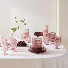 the table is set with pink glasses and plates