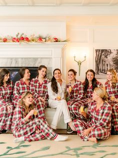 a group of women in matching plaid pajamas sitting on the floor and posing for a photo