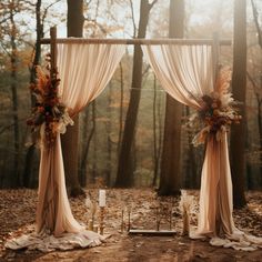 an outdoor wedding ceremony setup with drapes and flowers on the ground, surrounded by trees