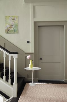 a vase with flowers sits on a small table in front of the door to an entryway