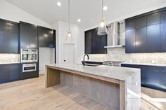 an empty kitchen with blue cabinets and marble counter tops, along with wooden flooring