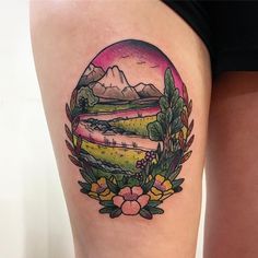 a woman's thigh with a landscape tattoo on it