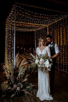 a bride and groom standing in front of some lights