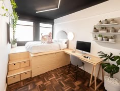 a room with a bed, desk and shelves on the wall next to a window