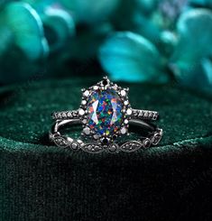 a ring with an opal colored stone in the center on a green velvet surface