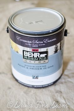 a can of behr premium plus paint sitting on top of a bed with white sheets