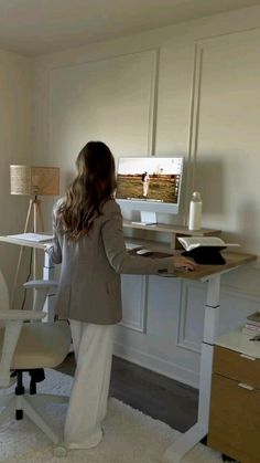 a woman standing in front of a desk with a computer on it