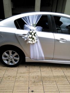 a silver car is decorated with white flowers