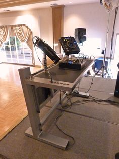 an electronic device sitting on top of a metal table in a room with hard wood floors