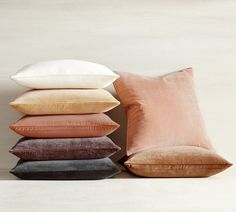 four pillows stacked on top of each other in different colors and sizes, with one pillow folded up to the side