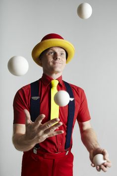 a man wearing a hat and suspenders juggling balls