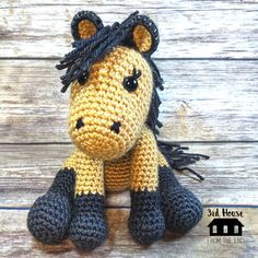 a crocheted stuffed horse sitting on top of a wooden floor