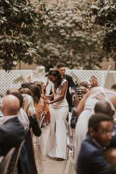 a bride and groom standing in front of an audience at a wedding ceremony with their arms around each other