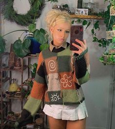 a woman taking a selfie in front of a mirror wearing a sweater with flowers on it