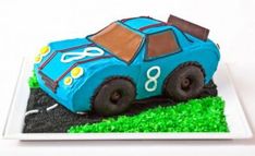 a cake shaped like a race car is on a plate with green grass and dirt