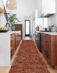 a kitchen area with wooden cabinets and an orange rug on the floor next to it