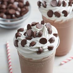 two cups filled with ice cream and chocolate chips next to candy canes on a table