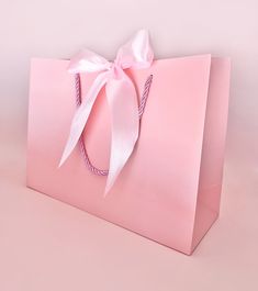 a pink shopping bag with a bow on the handle and ribbon tied around the front