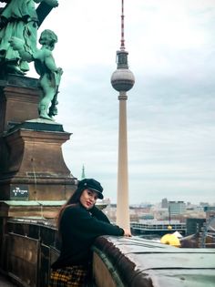 a woman standing on top of a bridge next to a statue