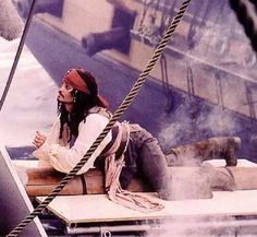 a man sitting on top of a boat next to a roped in area with other boats