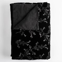 a black blanket with white flowers on it and a dark gray sheet folded over the edge