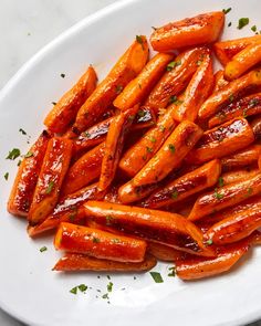 a white plate topped with sliced carrots covered in sauce