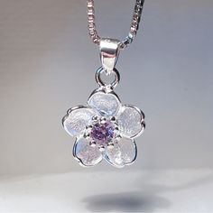 Gorgeous Sakura Flower Pendant. This Dainty, Elegant Pendant Features A Beautiful Silver Flower With A Simulated Purple Diamond Core. Pendant: 0.5” Necklace: 18" Blossom Color Sterling Silver Flower Jewelry, Blossom Colored Flower-shaped Sterling Silver Jewelry, Silver Necklace With Flower Charm For Anniversary, Silver Delicate Flower Charm Necklace, Silver Sterling Flower Pendant Necklace, Delicate Silver Flower Charm Necklace, Delicate Sterling Silver Round Flower Necklace, Silver Sterling Silver Flower Pendant Necklace, Silver Sterling Silver Pendant Flower Necklace