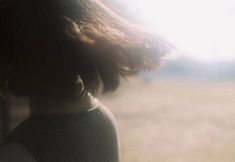 the back of a woman's head and neck, with grass in the background