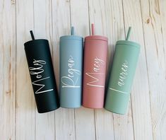 three personalized tumblers with straws in them sitting next to each other on a wooden surface