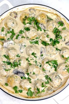 a pizza with mushrooms and parsley in a white sauce on a counter top, ready to be eaten