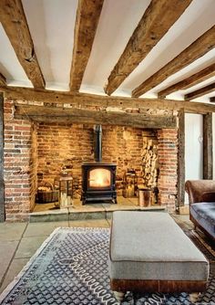 a living room with a couch, chair and wood burning stove in the middle of it