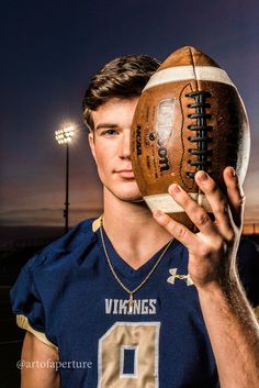 a man holding a football in front of his face