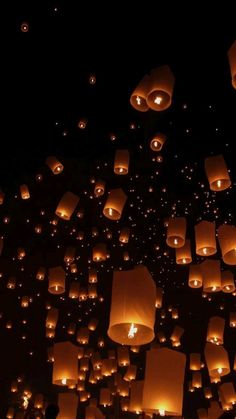 many lanterns are floating in the air at night