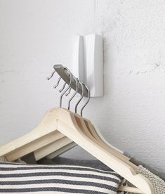 a wooden coat hanger with five clothes pins attached to it, hanging on a white wall