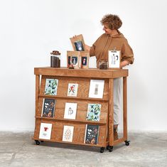 a woman standing behind a wooden table with books on it and an open book shelf