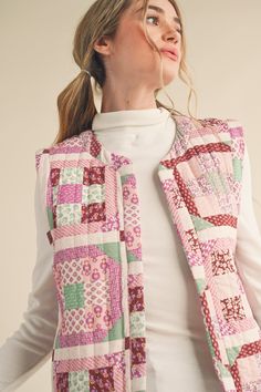 a woman wearing a pink and green patchwork vest with white turtle neck sweater underneath