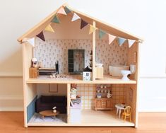 a doll house with furniture and accessories on the floor in front of a white wall