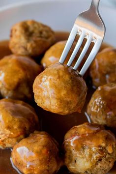 a fork is stuck into some meatballs in gravy