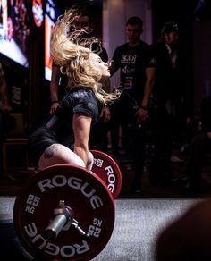 a woman squats on a barbell during a crossfit competition in a gym