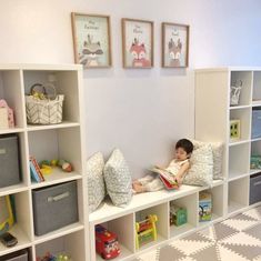 a little boy sitting on top of a white book shelf filled with lots of books