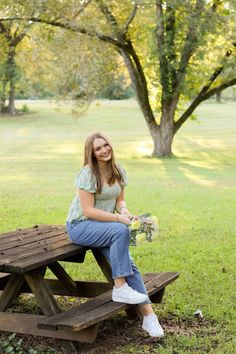 a woman sitting on a picnic table with flowers