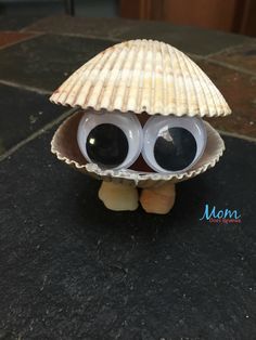 a small toy with big eyes and a shell on the ground