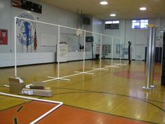 an empty gym with several volleyball nets in the middle and basketball hoop on the floor