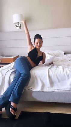 a woman laying on top of a bed with her arms in the air