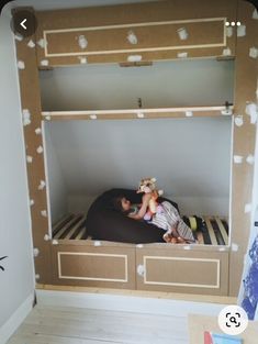 a child laying on top of a bunk bed in a room with white paint all over the walls