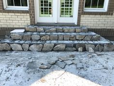 the steps are made out of rocks and cement in front of a house that is being renovated