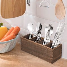 there is a basket with silverware and carrots in it on the kitchen counter