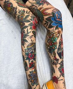 a woman with tattoos on her legs and leggings sitting on top of a bed