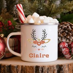 a white mug filled with marshmallows on top of a table next to christmas decorations