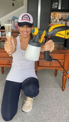 a woman is sitting on the floor holding a paintbrush and a driller in her hand